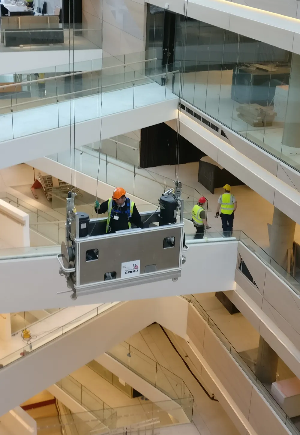 Crew in hi-vis working from a GPBMU cradle in a building atrium